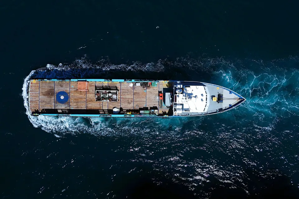 Embarcación de trabajo navegando en el mar, vista desde arriba.